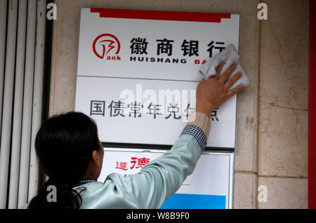 ---- Ein chinesischer Arbeiter reinigt eine Tafel in einer Filiale der Bank in Huishang Stadt Huaibei, der ostchinesischen Provinz Anhui, 6. November 2013. Huishang Verbot Stockfoto