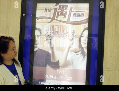 ---- Eine Chinesische filmgoer Spaziergänge hinter einem Plakat des Films "Buch der Liebe" in einem Kino in Yichang, Provinz Hubei, China 20. April 2016. Stockfoto