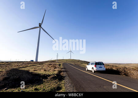 ------ Fährt ein Auto durch Windenergieanlagen in einem Windpark in der Stadt Zhangjiakou, North China Provinz Hebei, 3. Mai 2016. China hält den Rekord als Wor Stockfoto