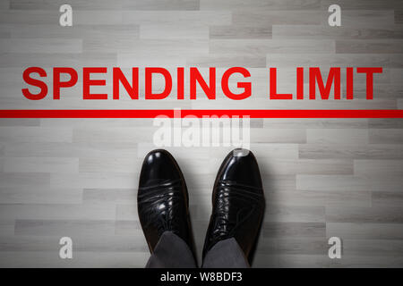 Der Geschäftsmann Fuß in Schwarze Schuhe stehen in der Nähe der Ausgabenlimite Rot verbotene Zeile Stockfoto