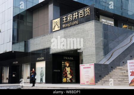 ---- Eine Frau steht vor einer Modeboutique Prada an einem Abteilung Speicher der Wangfujing in der Stadt Xi'an, Provinz Shaanxi im Nordwesten Chinas, Stockfoto