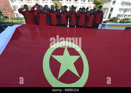 - - - - Junge chinesische Studenten vor eine Fahne mit dem Logo der Kommunistischen Jugendliga Chinas schwören während eines Patriotismus Bildung Veranstaltung in Li Stockfoto