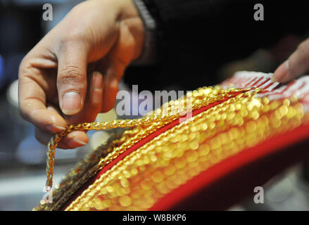 ---- Eine chinesische Angestellte zeigt Gold hand Ketten bei einem Juwelier in Lin'An, der ostchinesischen Provinz Zhejiang, 18. März 2016. China's Gold Reserv Stockfoto