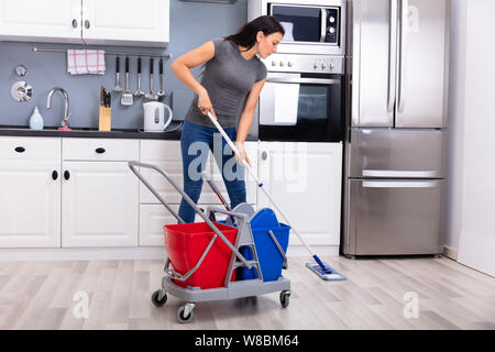 Gerne weibliche Hausmeister Reinigung Boden mit Mop In der Küche Stockfoto