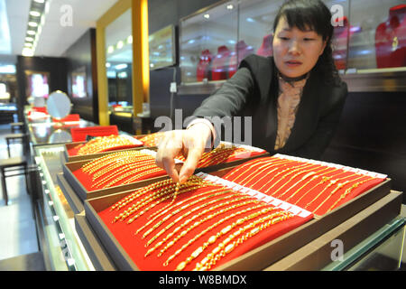 ---- Eine chinesische Angestellte zeigt Gold hand Ketten bei einem Juwelier in Lin'An, der ostchinesischen Provinz Zhejiang, 9. Februar 2016. China's Gold rese Stockfoto