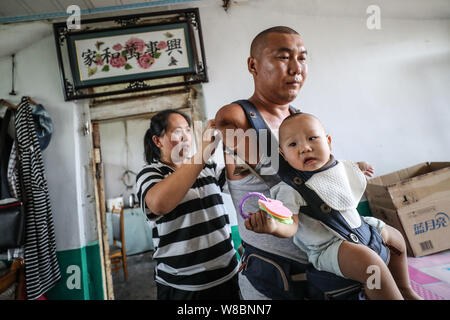 (190809) -- CHANGTU, August 9, 2019 (Xinhua) - Er Xiaoman, Ehefrau von Wang Gang, hilft, Wang Gang ihr Sohn Rourou zu Hause an hexi Dorf Liangjiazi Township, Changtu Grafschaft der Stadt Tieling, Provinz Liaoning im Nordosten Chinas, Aug 8, 2019 halten. Wang Gang, ein 33-jähriger Dorfbewohner von hexi Dorf der Provinz Liaoning, verlor seine Arme aufgrund einer versehentlichen elektrischen Schock im Alter von 13 Jahren. Nach Jahren der harten Praxis mit seinen Füßen, er kann nicht nur mit sich selbst, sondern auch einige einfache Hausarbeit und kümmern sich um seine kranke Mutter. Wang Gang heiratete er mit Xiaoman vor vier Jahren und Stockfoto