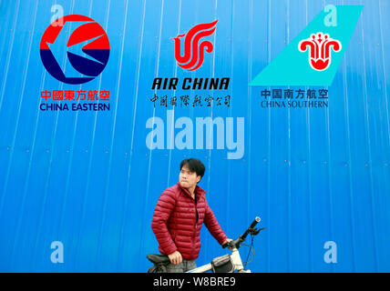 ---- Ein Radfahrer schiebt sein Fahrrad vor einem Namensschild mit Logos von (von links) China Eastern Airlines, Air China, China Southern Airlines i Stockfoto