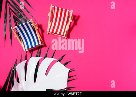 Flach am Strand Liegestühle, monstera und Palmblättern auf rosa Hintergrund mit kopieren. Sommer und Travel Concept. Kreative Banner. Stockfoto