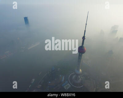 Der Oriental Pearl TV Tower, Front, und andere Hochhäuser und Wolkenkratzer sind vage in dichtem Nebel im Finanzviertel Lujiazui gesehen in Stockfoto