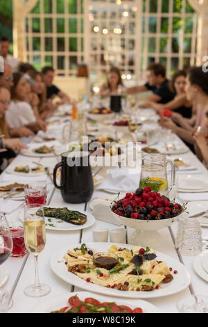 Die Gäste sitzen an langen Holztischen serviert zum Feiern. Stockfoto