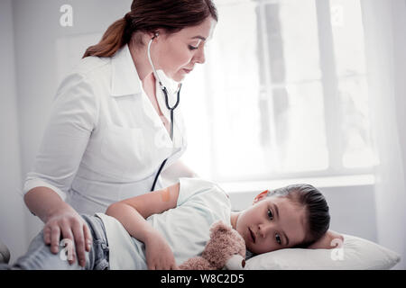 Nette weibliche Arzt über Ihre professionelle Stethoskop Stockfoto