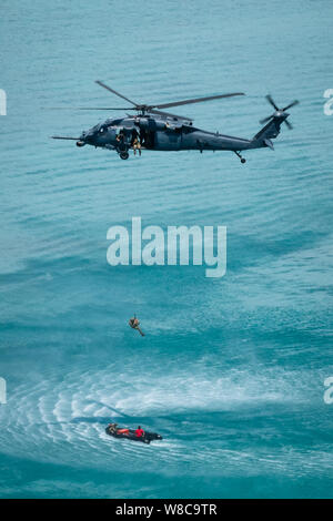 Ein HH-60G Pave Hawk vom 33. Rescue Squadron, senkt eine pararescuemen in ein Schiff im Meer während einer Operation, 26. Juli 2019, aus der Kadena Air Base, Japan. Die 33. und 31. RQS beide das gleiche Motto teilen, "diese Dinge, die wir tun, damit andere leben können." (aus den USA Air Force Foto von Airman 1st Class Matthew Seefeldt) Stockfoto