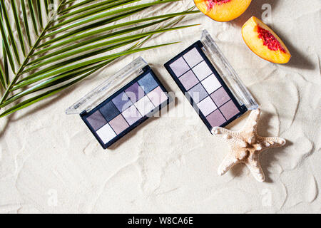 Bezaubernden Strand. Die Palette der Schatten mit quadratischen Nachfüllungen von hellen Früchten, Korallen umgeben, und Palm Blätter liegen auf dem weißen Sand. Nahaufnahme, Ansicht von oben. Stockfoto