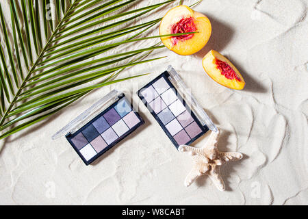 Bezaubernden Strand. Die Palette der Schatten mit quadratischen Nachfüllungen von hellen Früchten, Korallen umgeben, und Palm Blätter liegen auf dem weißen Sand. Nahaufnahme, Ansicht von oben. Stockfoto