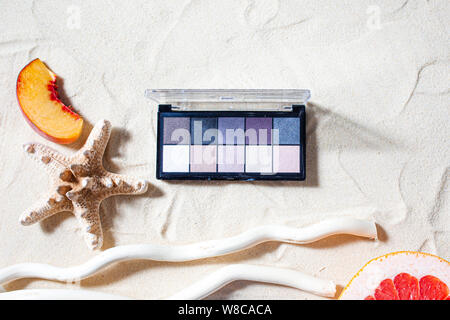 Bezaubernden Strand. Die Palette der Schatten mit quadratischen Nachfüllungen von hellen Früchten, Korallen umgeben, und Palm Blätter liegen auf dem weißen Sand. Nahaufnahme, Ansicht von oben. Stockfoto