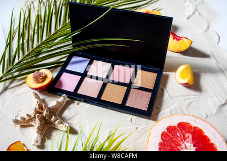 Bezaubernden Strand. Die Palette der Schatten mit quadratischen Nachfüllungen von hellen Früchten, Korallen umgeben, und Palm Blätter liegen auf dem weißen Sand. Nahaufnahme, Ansicht von oben. Stockfoto