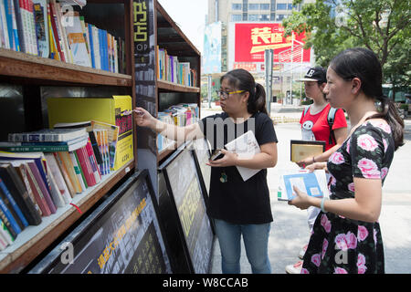 Eine Frau fällt Geld in einen Lock-Box für Bücher, die sie bei der staffless Ehrlichkeit Buchhandlung in Xinjiekou Straße gekauft, Nanjing, China Jiangsu Stockfoto