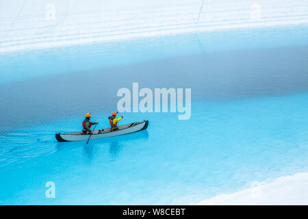 Zwei Männer, ein aufblasbares Kanu paddeln auf einem blauen Pool auf der Matanuska Gletscher in der Wildnis von Alaska. Der Blaue See ist ein Supraglazialen See, Stockfoto