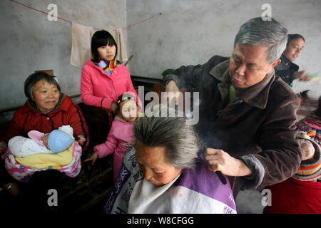 Chinesische friseur Wang Weimei, rechts, verwendet ein paar heiße Feuer Zangen das Haar eines Kunden in seinem Geschäft in der Stadt Perm, Jinshi Santai County, Mianyang ci Stockfoto