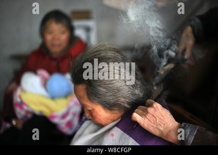 Chinesische friseur Wang Weimei, rechts, verwendet ein paar heiße Feuer Zangen das Haar eines Kunden in seinem Geschäft in der Stadt Perm, Jinshi Santai County, Mianyang ci Stockfoto