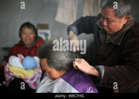 Chinesische friseur Wang Weimei, rechts, verwendet ein paar heiße Feuer Zangen das Haar eines Kunden in seinem Geschäft in der Stadt Perm, Jinshi Santai County, Mianyang ci Stockfoto