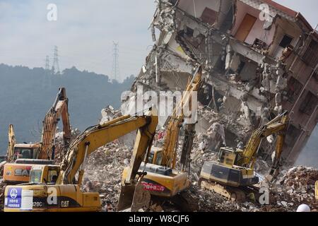 Maschinen werden verwendet, um einem eingestürzten Gebäude auf dem Gelände der Erdrutsch, der die Hengtaiyu, Liuxi und Dejicheng Industrieparks Hit zu demontieren, in Stockfoto