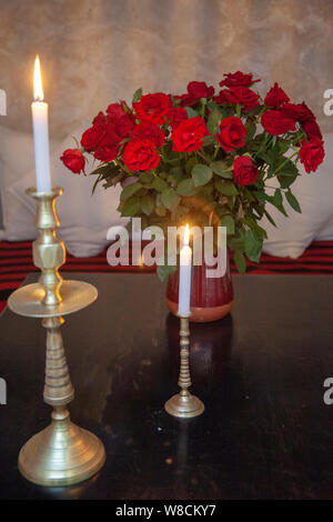 Rosen in Vase und Kerzen auf dem Tisch Stockfoto