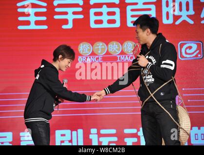 Chinesische Schauspieler, Deng Chao, rechts, spricht, wie er mit seinen Händen hält die Schauspielerin Frau Sun Li bei einer Pressekonferenz zur Premiere seines neuen Films 'Devil Stockfoto