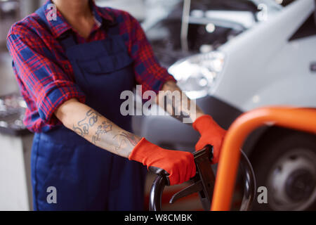 Mechaniker inn der Garage arbeitet mit schweren orange-farbige Geräte in einer Nahaufnahme. Stockfoto