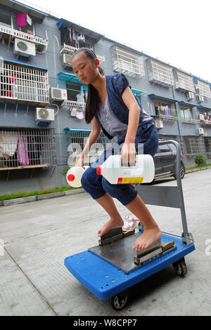 Ein 13-jähriges Mädchen mit dem Zunamen Xie trägt Wasser in Flaschen, mit einem Gewicht von 5 Kilogramm, während die ständigen barfuss auf den Blades von Fleisch Hackmesser in Wenzhou ci Stockfoto