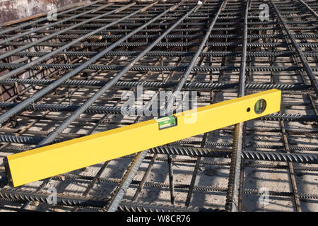 Gebäude gelb gefärbte Ebene Werkzeug auf der steel Grid der Wohngebäude Basis Verstärkung. Stockfoto