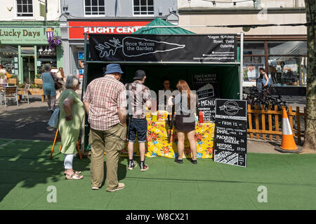 Im Sommer stehen Menschen Schlange, die an einem Straßenfoodstand für vegane Küche Lebensmittel kaufen York North Yorkshire England Großbritannien GB Großbritannien Stockfoto