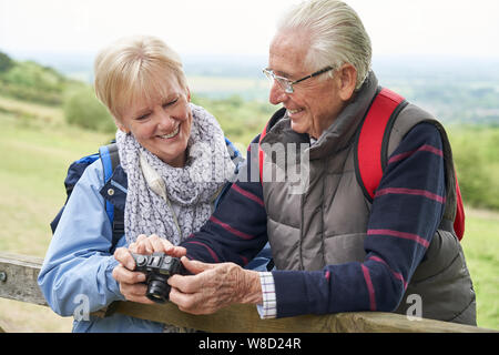Senior Paar Wandern in der Landschaft stehend durch Tor und die Fotos mit der Kamera Stockfoto
