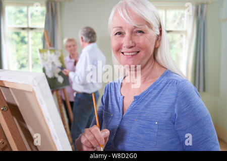 Portrait von Senioren Frau Teilnahme an Malerei Klasse mit Lehrer im Hintergrund Stockfoto