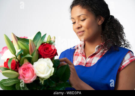 Studio Shot der weiblichen Florist arrangieren Blumenstrauß aus Lilien und Rosen vor weißem Hintergrund Stockfoto