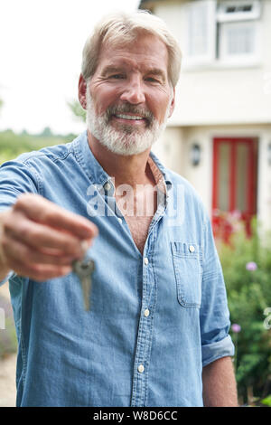 Portrait von reifer Mann im Garten Vor der Traumhaus in die Landschaft halten Tasten Stockfoto