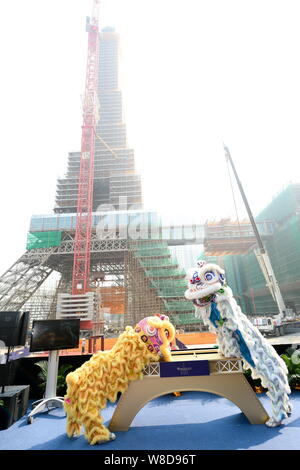 Animateure führen Sie einen Löwen Tanz auf dem Richtfest der Hälfte große Nachbildung des Eiffelturms auf der Baustelle des Pariser Macau Stockfoto