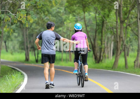 Paar mittleren Alters zu Fuß mit dem Fahrrad im Park Stockfoto