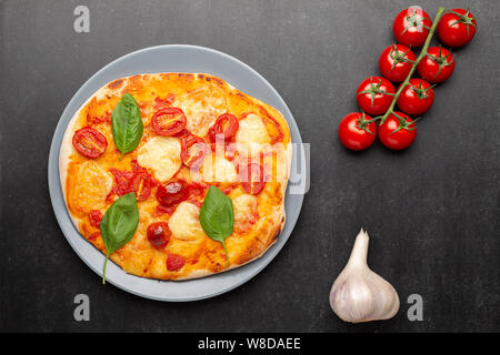 Hausgemachte Pizza Margarita mit Tomaten, Basilikum und Mozzarella auf grau Platte, Ansicht von oben Stockfoto