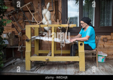Eine Frau, die bei ihrer Arbeit im Dorf von Botiza, Maramureș, Rumänien Webstuhl. Das Dorf ist bekannt für seine handgewebten Teppiche und Teppichböden aus Wolle bekannt Stockfoto
