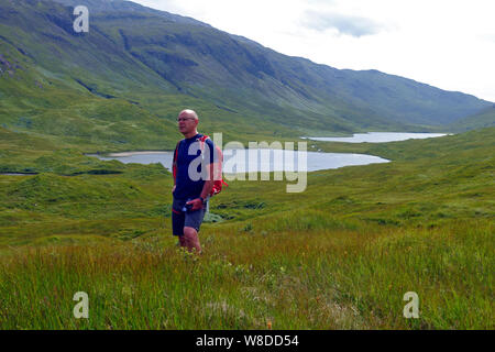 Mann in Glen Mehr auf der Isle of Mull an den drei Seen (nur zwei sichtbar sind, Loch ein Ellen und weiter hinter Loch Airde Glais Stockfoto