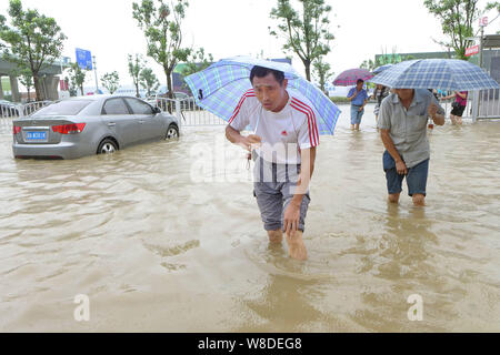 Fußgänger gehen auf eine überflutete Straße in einem starken Regen von Typhoon Goni in Shanghai, China, 24. August 2015 verursacht. Shanghai hat ein Wasser Welt der s werden Stockfoto