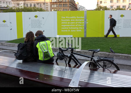 Junges Paar auf einer Bank vor der Horten bei einem Umbau/Modernisierung von Piccadilly Gardens Manchester, England UK. foto DON TONGE Stockfoto