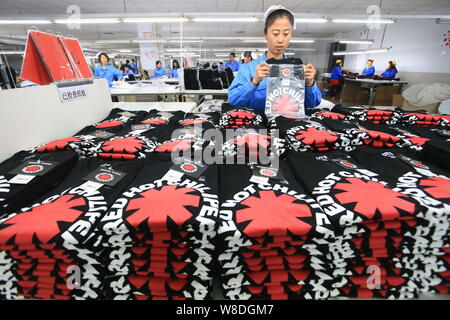 ---- Eine weibliche chinesischer Arbeiter Pakete Kleidung bei einer Textilfabrik in Jimo Stadt, der ostchinesischen Provinz Shandong, 16. Dezember 2014. China's workin Stockfoto