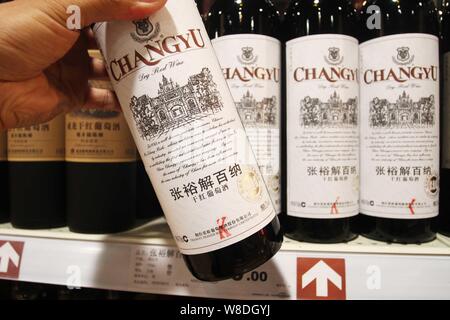 ---- Ein Kunde Geschäfte für eine Flasche Changyu trockener Rotwein in einem Supermarkt in der Stadt Xuchang, Zentrale China Provinz Henan, 16. Juni 2013. In li Stockfoto