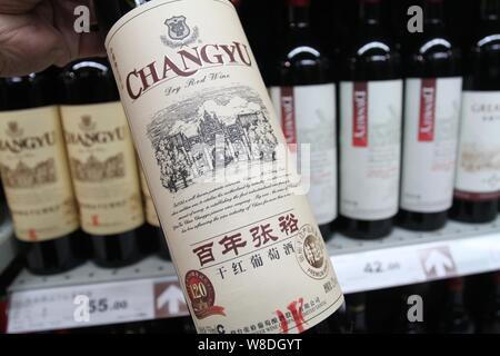 ---- Ein Kunde Geschäfte für eine Flasche Changyu trockener Rotwein in einem Supermarkt in der Stadt Xuchang, Chinas Provinz Henan, am 24. März 2013. Yanta Stockfoto