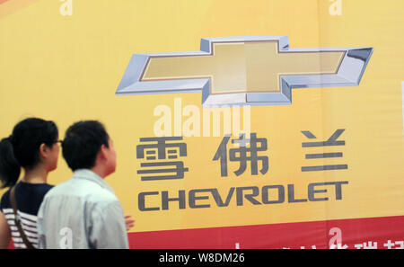 ---- Besucher vorbei an einer Werbung für Chevrolet von Shanghai GM, ein Joint Venture zwischen der SAIC Motor und General Motors, während ein Automobil Stockfoto