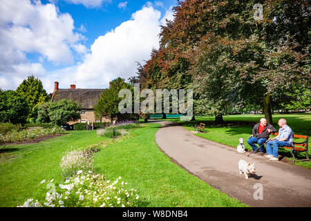 Northampton GROSSBRITANNIEN. 9. August 2019. Wetter. Nach schweren nächtlichen Regen Sonnenschein und blauen Wolken erscheinen am frühen Morgen in Abinton Park über dem Reetdachhaus in der oberen Park, mit ein paar Herren saß auf einer Bank in einem Chat. Credit: Keith J Smith./Alamy leben Nachrichten Stockfoto