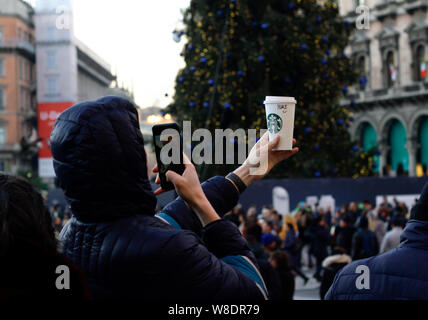 Mailand, Italien - Dezember 14, 2018: Ein junger Mann hält ein Starbucks Pappbecher und nimmt ein Foto von ihm mit seinem Handy. Stockfoto