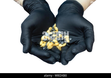 Mädchen Kosmetikerin in Schwarz medizinische Handschuhe mit Granulat von Wachs für Haarentfernung in der Form eines Herzens auf dem Palm Stockfoto